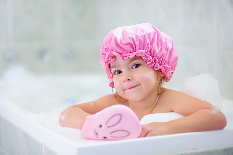 Little girl peaking out of tub