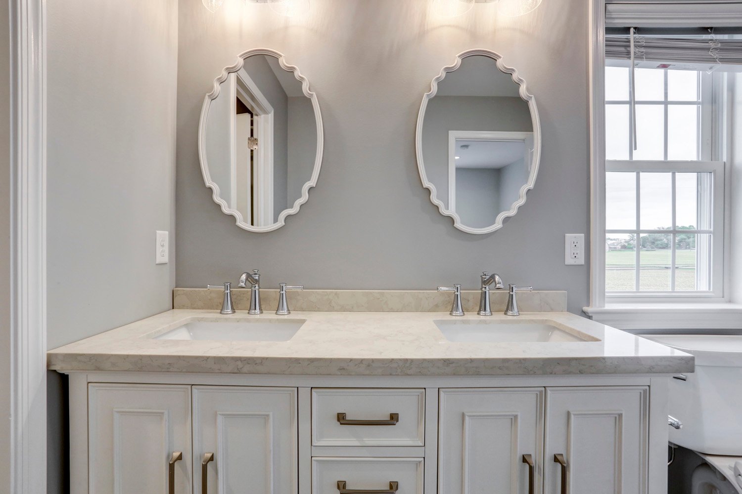 Leola Master Bathroom Addition with double vanity with white cabinets and intricate oval mirrors