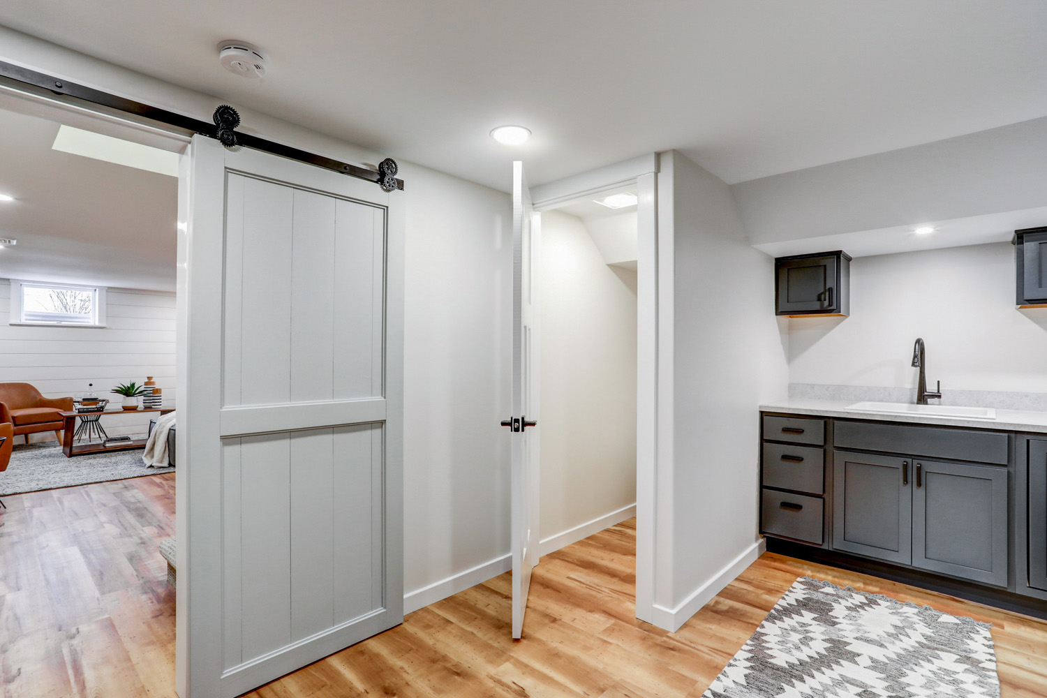 Laundry room with toilet room and sliding barn door in Lancaster Basement Remodel