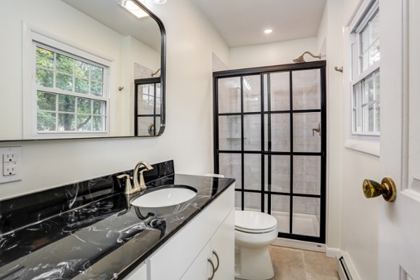 Bathroom remodel in Lancaster with black vanity countertop and farmhouse shower doors