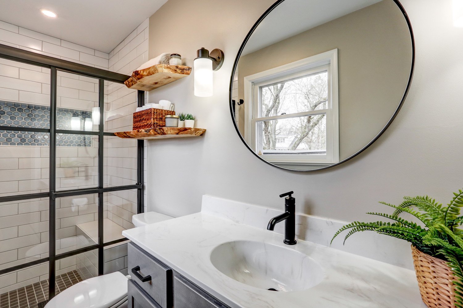 Round mirror and black faucet in Lancaster bathroom remodel