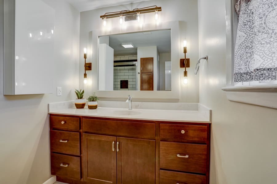 Bathroom remodel with stained wood vanity and industrial sconces