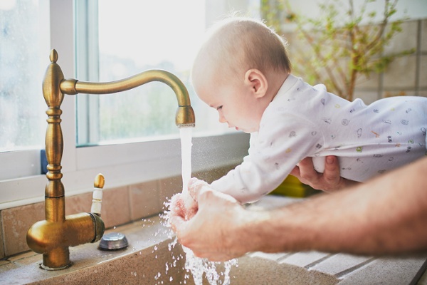 Baby washing her hands in sink