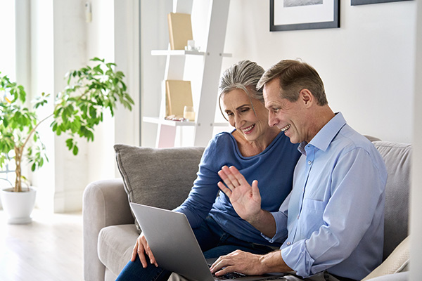 Man and woman waving at the computer during a virtual consultation